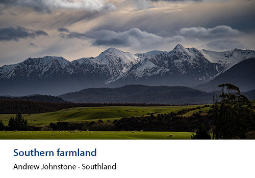 Farmland with a cloudy sky and mountains in the background