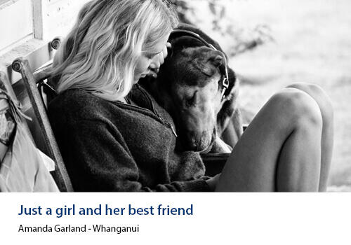 A black-and-white photo of a young woman sitting with her dog’s head resting lovingly on her shoulder. Caption: Amanda Garland, Whanganui.