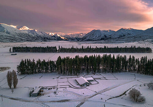 a snow covered farm at sunset