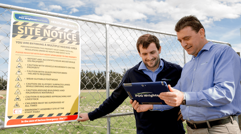 PGG Wrightson staff standing next to a Hazard site notice