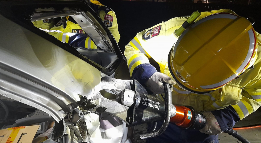 FENZ Volunteer using jaws of life to cut vehicle.